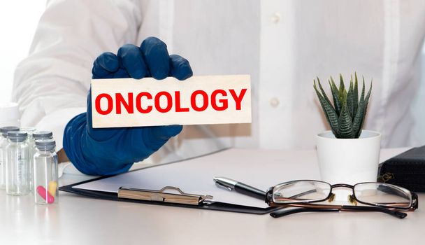 Dokter houdt een kaart bij met de naam van de diagnose - oncologie. Selectieve focus. Medisch concept - Foto, afbeelding