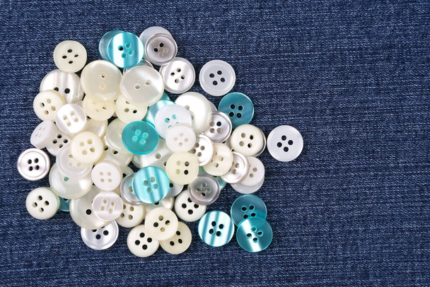 Kumaş arka plandaki kıyafetler için plastik parlak düğmeler. Moda ve giysi. Fabrika endüstrisi - Fotoğraf, Görsel