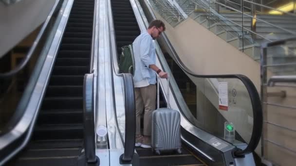 мужчина-путешественник с чемоданом стоит на эскалаторе - Кадры, видео
