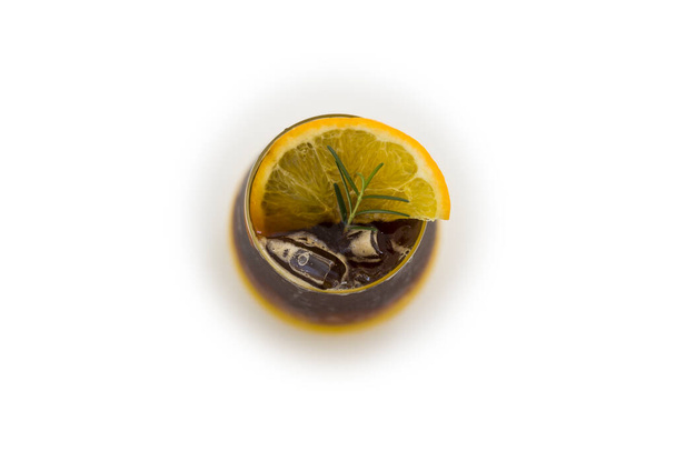 Освіжаючий келих американської кави з льодом, змішаної з апельсиновим соком, прикрашеним розмарином і нарізаним апельсином, на білому тлі. Вид зверху. альтернативне пиття для здорового способу життя з органічного трав'яного інгредієнта
. - Фото, зображення