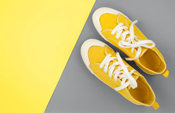 Нові пари жовтих кросівок на сіро-жовтому тлі з копіювальним простором. Стиль життя кросівки, спортивне взуття
. - Фото, зображення