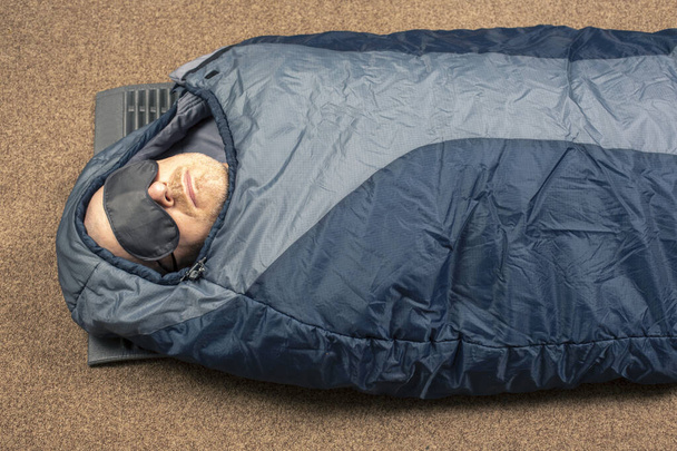 Der Mann schläft im Schlafsack. Artikel für Tourismus und Camping - Foto, Bild