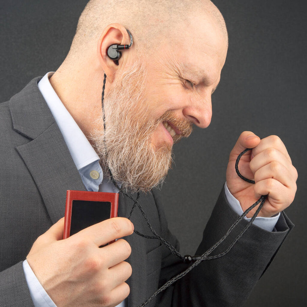 bearded man enjoys listening to his favorite music through an audio player in small headphones. audiophile and music lover. music and hi-fi sound. - Photo, Image