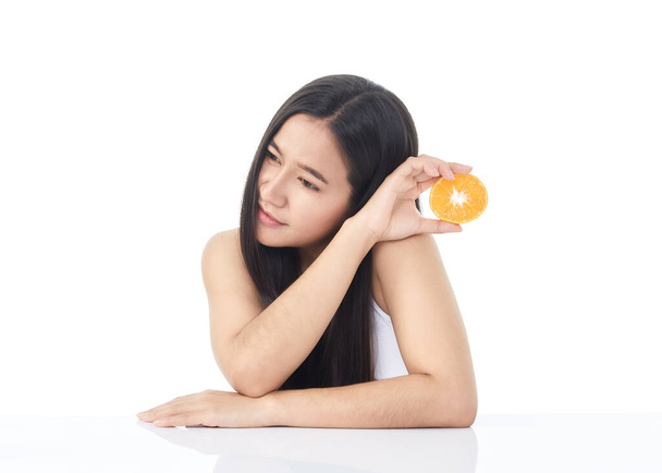 Ідеальний свіжий портрет молодої азіатської вродливої дівчинки з оранжевими шматками в руці, ізольованої на білому тлі. - Фото, зображення