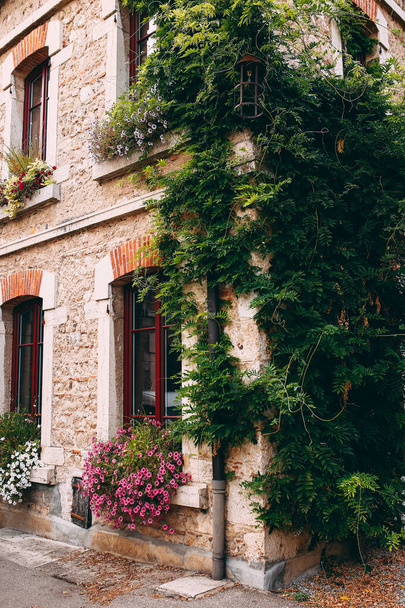 Обличчя старих кам'яних будівель у Перуж, червоні вікна, квіти, Франція. Фотографія високої якості - Фото, зображення