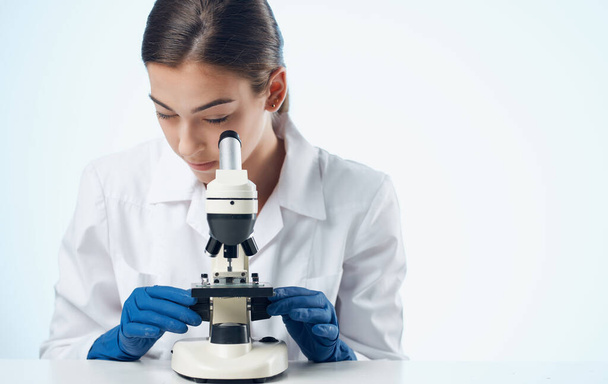 женщина с микроскопом за столом в лаборатории исследования бактерий микроорганизмов - Фото, изображение
