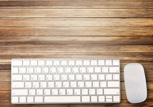 Вид зверху з міні-бездротовою клавіатурою та мишкою на фоні коричневого дерева столу. Копіювати місце для вашого дизайну
. - Фото, зображення