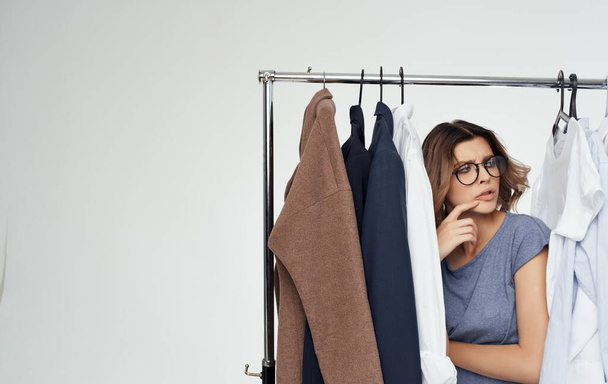 όμορφη γυναίκα με γυαλιά στέκεται κοντά ρούχα κοστούμια ντουλάπα Μοντέλο - Φωτογραφία, εικόνα