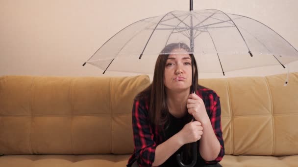 Pensive woman hide from flowing water under clear umbrella - Záběry, video