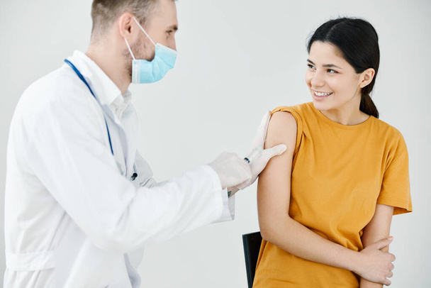 Arzt klebt einer glücklichen Patientin eine Injektion mit Klebeband auf die Schulter  - Foto, Bild