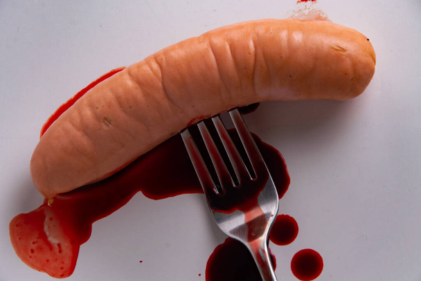 animal food rejection concept: blood flows from a forked sausage, short focus - Photo, Image