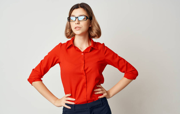 Mujer de negocios en una camisa roja pantalones azules y gafas sobre un fondo beige Copiar espacio - Foto, imagen