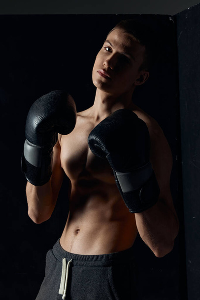 athlete in boxing gloves on black background portrait cropped view  - Zdjęcie, obraz