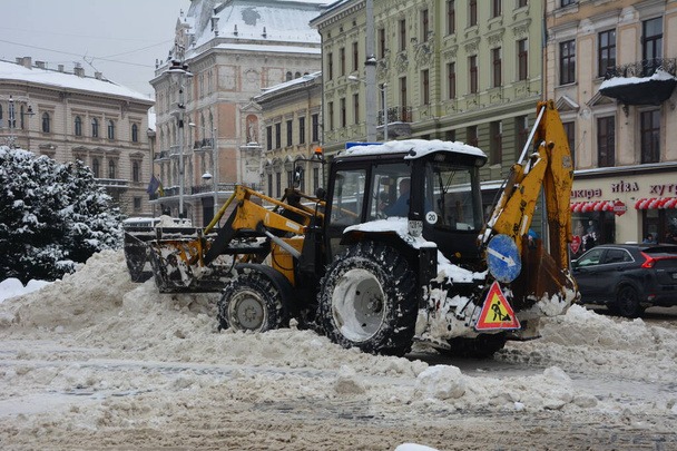 Olen Lviv. Ukrainassa. Helmikuu 2021.Lumenpoistotraktori pyörivällä harjalla lakaistaan lunta jalkakäytävällä pengerryksellä puistossa. traktori kauha ja automaattinen harja poistaa lunta. Kunnallishallinto - Valokuva, kuva