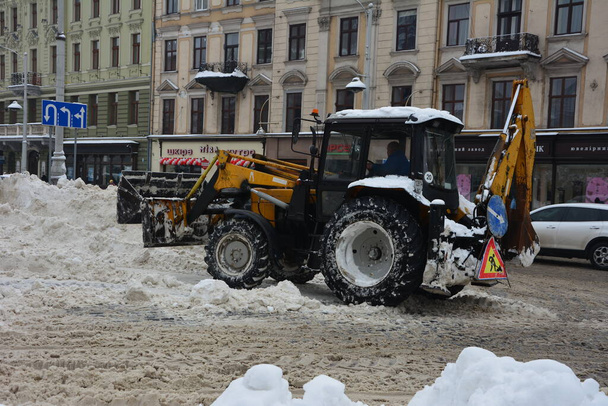 Lviv. Ukrayna. Şubat 2021 'de kar temizleme traktörü döner fırçayla karları parktaki toprak zeminden süpürüyor. Çekici kepçeli ve otomatik fırçalı kar kaldırır. Belediye Kamu Hizmeti - Fotoğraf, Görsel