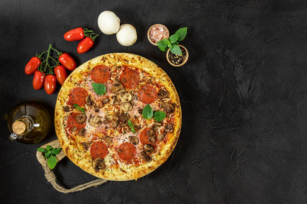 Pizza italiana Napoli quente com presunto e cogumelos no fundo escuro. Espaço de cópia, vista superior, entrega de fast food - Foto, Imagem