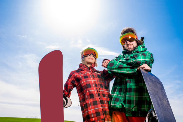 Cool couple with snowboards in sport wear standing on the grass - Photo, Image