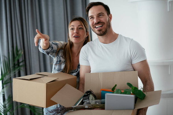 Boyfriend and girlfriend are moving in a apartment. Young couple are unpacking their belongings. - Foto, Imagem