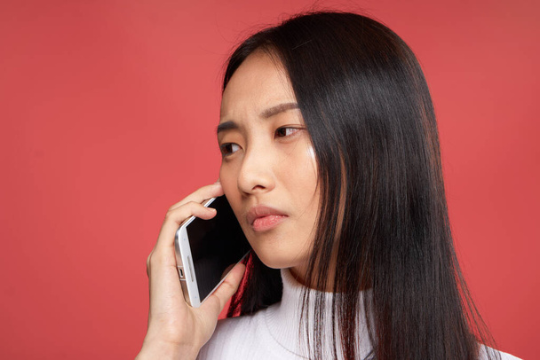 симпатичная брюнетка, разговаривающая по телефону крупным планом на красном технологическом фоне - Фото, изображение