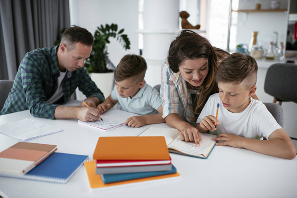 Parents helping kids with their homework. Little boys learning at home. - Фото, зображення
