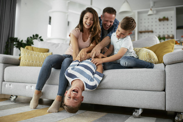 Молодая семья наслаждается дома. Счастливые родители с сыновьями веселятся. - Фото, изображение