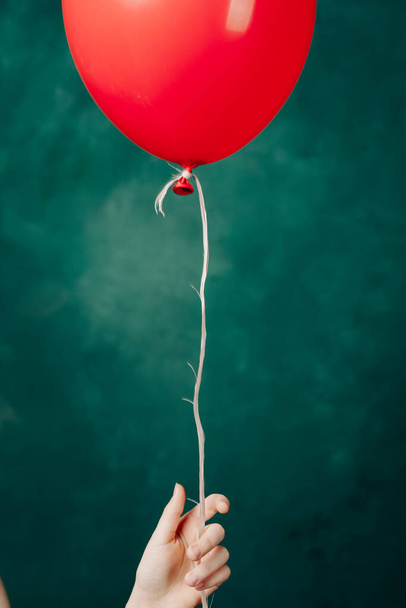 czerwony balon w dłoni na zielonym tle leci w górę z bliska - Zdjęcie, obraz