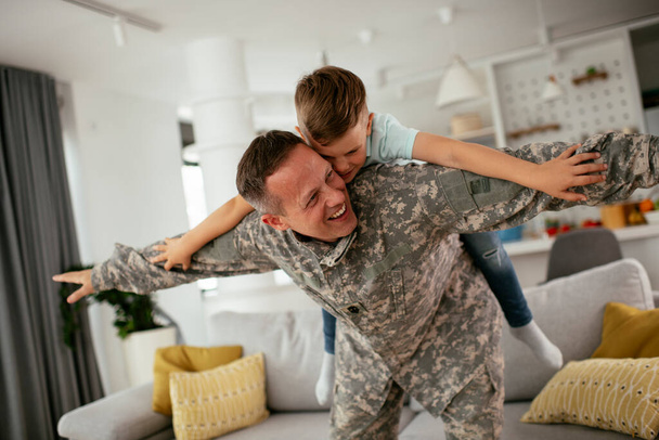 Солдат розважається зі своїм сином вдома. Батько і син грають у вітальні
. - Фото, зображення
