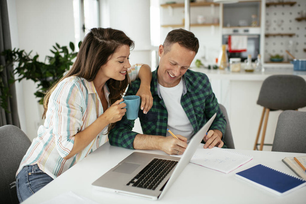 Onnellinen nuori pari käyttää kannettavaa tietokonetta kotona - Valokuva, kuva