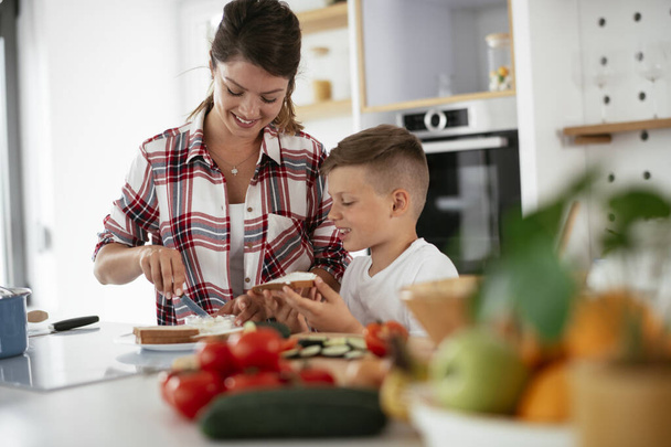 Mutter und Sohn frühstücken. Mutter und Sohn essen Sandwiches in Küche - Foto, Bild