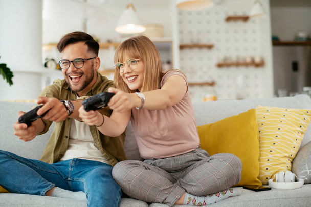 couple playing video game on sofa at home - Photo, Image