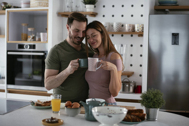Loving couple drinking coffee while preparing the breakfast. - Foto, Bild