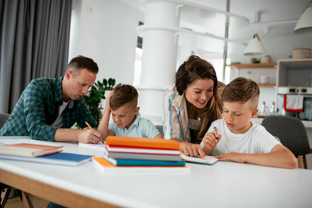 Eltern helfen Kindern bei den Hausaufgaben. Kleine Jungen lernen zu Hause. - Foto, Bild