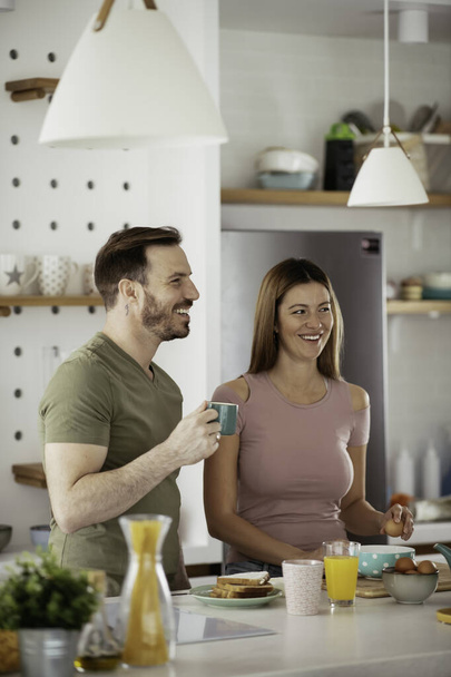 Loving couple drinking coffee while preparing the breakfast. - 写真・画像