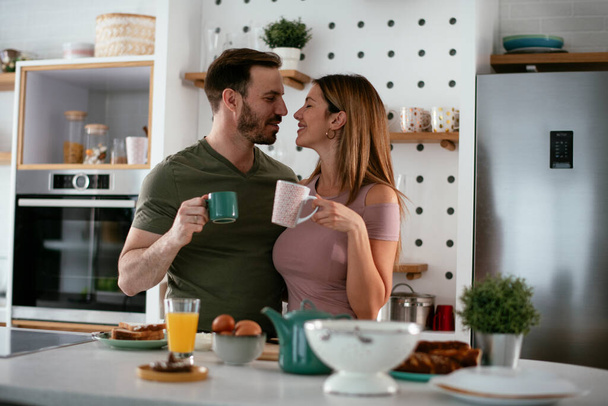 Loving coppia bere caffè mentre si prepara la colazione. - Foto, immagini