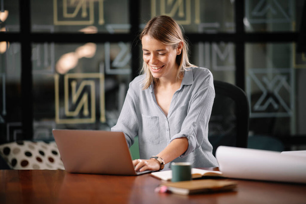 Giovane donna d'affari godendo mentre si lavora sul computer portatile in ufficio - Foto, immagini