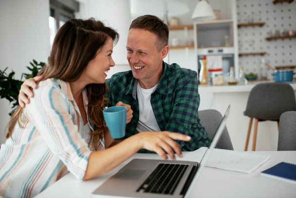 Glückliches junges Paar benutzt Laptop zu Hause - Foto, Bild