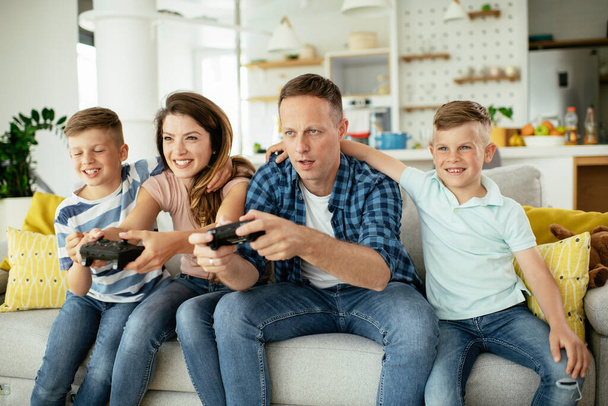  Felice coppia amorevole stanno giocando ai videogiochi con i bambini a casa. - Foto, immagini