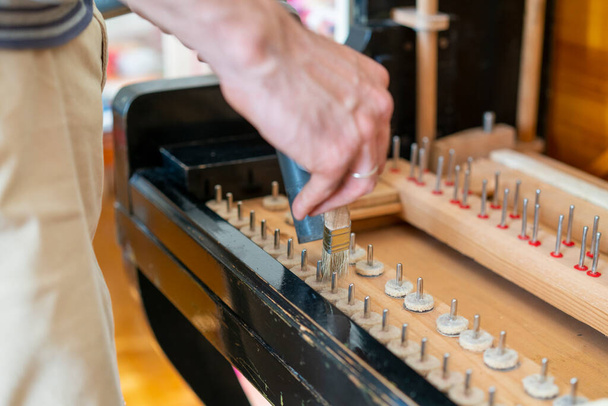 Setting up an old piano. The master repairs an old piano. Deep cleaning the piano. Hands of professional worker repairing and tuning an old piano. toned. - Photo, Image