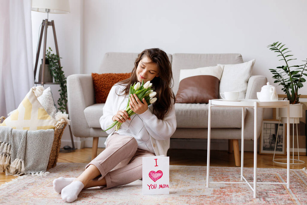 giovane mamma con un mazzo di fiori in soggiorno in vacanza - Foto, immagini