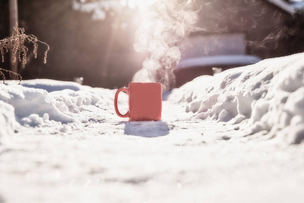 Dampende kop hete koffie, thee of chocolade in de koude verse witte sneeuw, Winter, gezellig, drinken, besneeuwde dag concept achtergrond in de natuur - Foto, afbeelding
