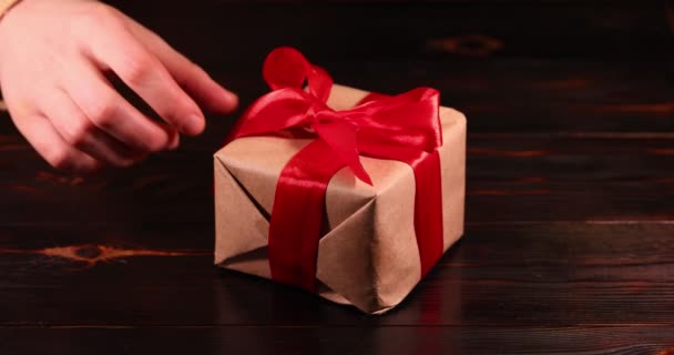 De hand van de vrouw maakt het rode lint op de geschenkdoos los. Super slow motion. - Video