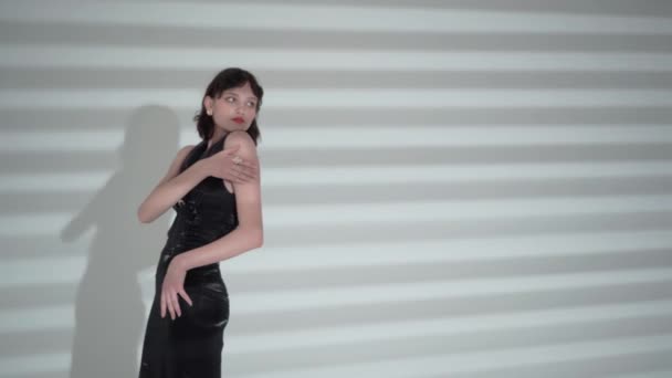 Meisje, fashion model op een witte achtergrond, verlicht door bewegende lichtstralen. Vrije ruimte voor invoeging. - Video
