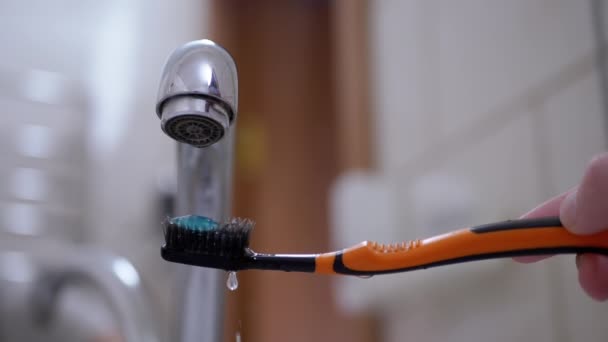Gocce d'acqua dal rubinetto cadono lentamente sullo spazzolino da denti a setole nere. Rallentatore - Filmati, video