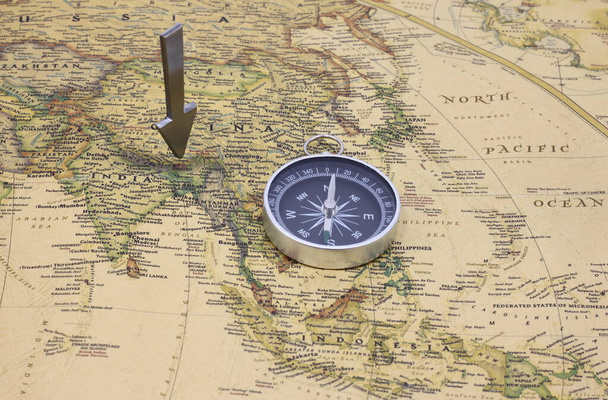 Classic round compass on background of old vintage map of world as symbol of tourism with compass, travel with compass and outdoor activities with compass - Photo, Image
