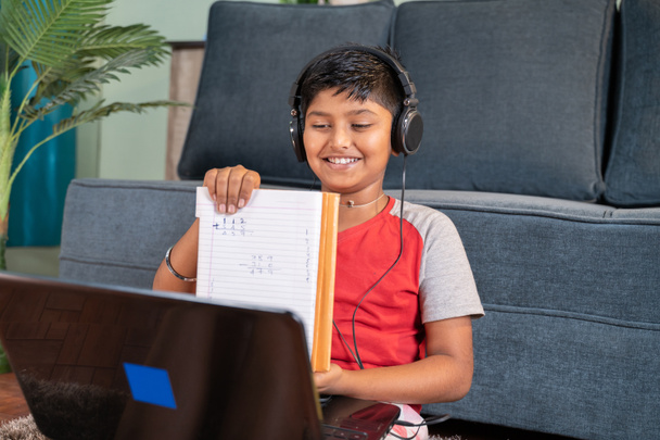 Ребенок взаимодействует во время онлайн-урока, показывая решенные задачи репетитору на ноутбуке - концепция нового нормального виртуального образования и электронного обучения благодаря пандемии covid-19. - Фото, изображение