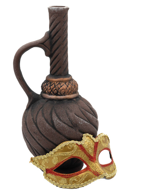 A traditional golden Venetian carnival mask next to an ornate clay wine bottle. The photo is isolated on a white background. The concept of the annual Brazilian festival. - Photo, Image