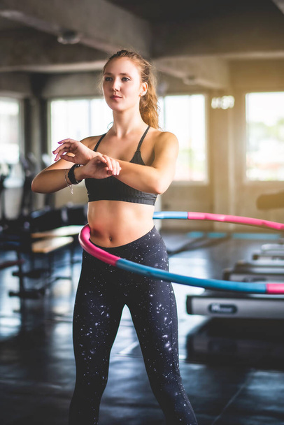 Spor salonunda egzersiz yaparken hula hoop yapan güzel, genç, çekici beyaz bir kadın. Sağlıklı spor yaşam tarzı, fitness, sağlıklı ve egzersiz konsepti.  - Fotoğraf, Görsel