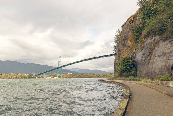 Vancouver seawall μονοπάτι γύρω από Stanley πάρκο με Lion πύλη γέφυρα φόντο σε κινηματογραφικό τόνο στο British Columbia, Καναδά - Φωτογραφία, εικόνα