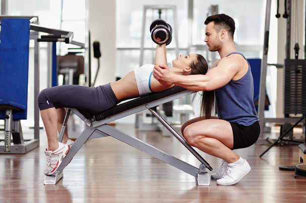 Personal trainer helping woman at gym - Foto, Bild