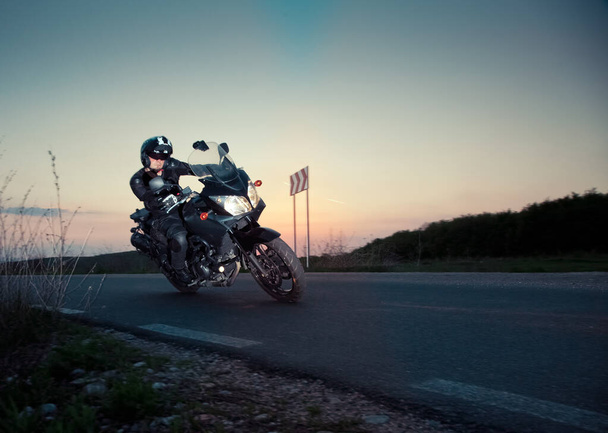 silueta del jinete en una motocicleta conduciendo al atardecer - espacio para su texto - Foto, Imagen